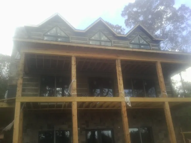 Dormers and porch framing on a large log home under construction — Roof Coating work by our crew in Carpenter