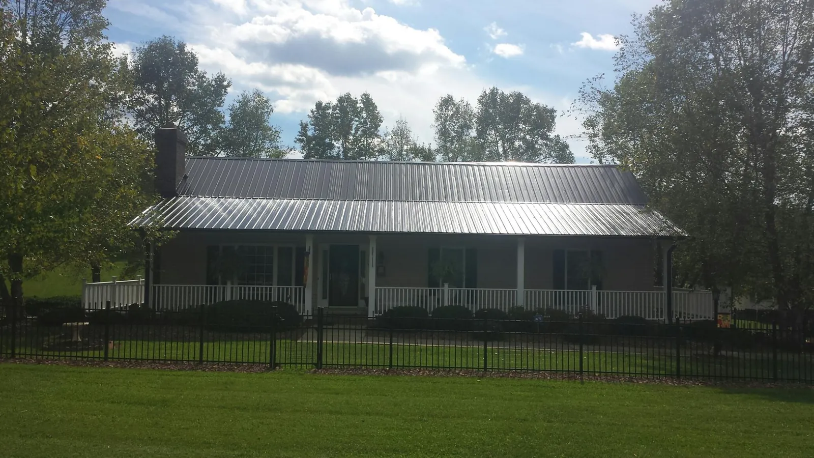 Gray metal roof on a brick ranch with a full width front porch — Gutter Guard Installation work by our crew in Carpenter